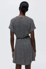 Vestido corto entallado color gris oscuro con cuello redondo, mangas raglán cortas y cierre oculto en la espalda. Incluye un cinturón fino negro con hebilla metálica decorativa.