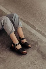 Sandalia de cuero color tostado con tiras anchas, tira en el talón y hebilla metálica rectangular ajustable. Cuenta con suela de goma con tacón bajo y plataforma.