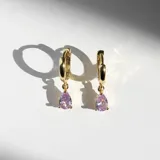 Par de aros dorados tipo argolla con dije colgante en forma de lágrima color lavanda.