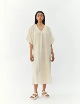 Vestido largo color crema, de corte amplio y mangas cortas.