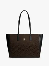 Cartera tipo tote de Tommy Hilfiger con diseño jacquard de monogramas TH en color marrón y laterales en negro. Cuenta con asas superiores fijas y logo metálico dorado en el frente.