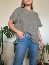 Chaleco tejido color verde oliva, con cuello en v y diseño de trenzas y ochos. Silueta oversize.