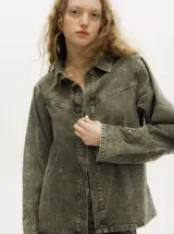 Campera de denim gastado color marrón, de corte holgado y ligero, con cuello camisero, cierre frontal de botones y detalles de botones en los puños.
