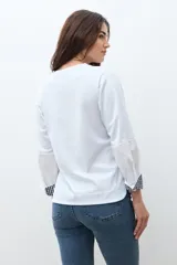 Remera blanca de manga larga con cuello redondo y puños con estampado de cuadros vichy en azul y blanco.