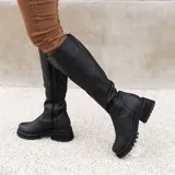 Bota de caña alta confeccionada en cuero vacuno, con suela de goma tipo track y cierre lateral interno. Presenta una punta redonda y diseño de estilo robusto.