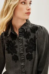 Camisa de liocel color gris oscuro con bordado de flores negras en las mangas largas abullonadas.