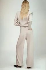 Pantalón de tiro alto en color beige, con diseño de pierna recta y costuras verticales marcadas. Presenta cierre frontal con cremallera y un botón negro en contraste.