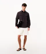 Camisa de hombre de corte regular confeccionada en terciopelo de algodón, con cuello clásico, cierre frontal de botones y dos bolsillos con solapa en el pecho.