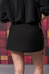 Pollera short negra con corte irregular y bolsillos delanteros con solapa.