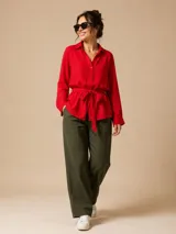 Camisa de seda color celeste, con cuello camisero, mangas largas y lazo ajustable en la cintura que genera un efecto fruncido.