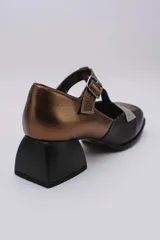 Zapato Mary Jane de cuero color bronce y dorado, con puntera redondeada, tira sobre el empeine con hebilla y tacón cuadrado.