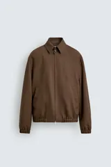 Cazadora regular fit marrón confeccionada en pura lana, con cuello solapa, cierre frontal de cremallera y bolsillos de vivo en la cadera. Presenta acabados con elástico en los puños y el ruedo.