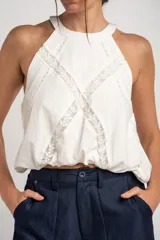 Top de viscosa y poliamida color blanco, con cuello halter y detalles de inserciones de encaje transparente formando una equis en el frente.