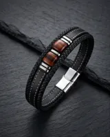Pulsera de diseño masculino compuesta por una banda de cuero sintético trenzado en color negro, con detalles centrales de acero y piedras naturales ojo de tigre.
