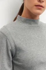 Polera de algodón color blanco, con cuello alto y mangas tres cuartos. Presenta un diseño ajustado al cuerpo con costuras decorativas en las sisas.