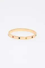 Pulsera rígida tipo esclava de aleación metálica dorada, decorada con pequeñas circonitas incrustadas en forma de corazón de diversos colores y cierre de bisagra.