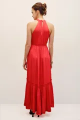 Vestido largo color rojo, sin mangas, con cuello halter fruncido, cintura elastizada y falda con volados en la parte inferior.