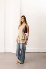 Vestido corto sin mangas de encaje negro, con escote bote y terminación de volados superpuestos.
