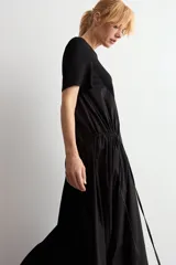 Vestido largo negro oversized con cuello redondo, mangas cortas y detalle fruncido en la cintura con cordón ajustable.