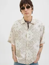 Camisa de manga corta con cuello resort, confeccionada en una mezcla de algodón y lino. Presenta un diseño estampado con motivos tipo damasco en tonos neutros y un corte amplio.