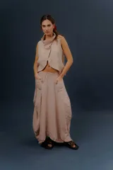 Pollera larga de lino color gris topo, de diseño amplio con volumen, movimiento y bolsillos delanteros. Cuenta con elástico en la cintura y detalles de pinzas y sobretelas en los laterales.