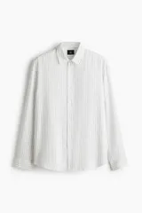 Camisa blanca de manga larga con rayas verticales finas en gris, cuello inglés, tapeta clásica de botones y bajo redondeado.