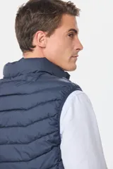 Chaleco capitoneado de color azul marino con capucha desmontable y cierre frontal. Diseño acolchado con costuras horizontales.