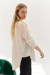 Camisa color crema de lyocell con cuello clásico, cierre frontal con botones, bolsillo de parche en el pecho y pespuntes a contraste en negro.