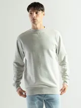 Buzo de felpa con cuello redondo, diseño liso y corte clásico. Presenta puños y ruedo acanalados, con un pequeño detalle de etiqueta en el lateral inferior.