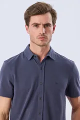 Camisa de piqué lisa color celeste, de manga corta, con cuello camisero y cierre frontal de botones oscuros.