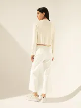 Pantalón blanco de tiro medio con cierre niquel lateral, tajos laterales en la bota, bolsillo ojal y pinza de entalle en la espalda.