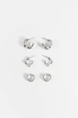 Set de tres pares de aros plateados de diseño variado, incluyendo argollas texturizadas, argollas angulares y aros pequeños tipo huggie.