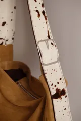 Bolso tipo hobo de gamuza color naranja quemado, con correa ancha de tela color bordó.