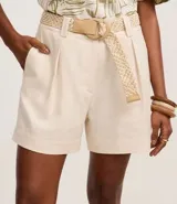 Short recto de cintura alta color crudo, confeccionado en viscolino, con trabillas en la cintura, pliegues y cierre tradicional. Incluye cinturón de rafia artificial con hebillas de argollas.