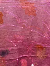 Mantel rectangular de lino color rosa con estampado de hojas y flores en tonos naranja, marrón y blanco.