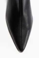 Botines de cuero negro con caña elástica, punta fina y taco fino de altura media.