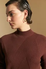 Polera de cuello alto en color blanco, confeccionada en tejido acanalado con un diseño geométrico de relieve que crea un efecto visual estilizado. Presenta un corte al cuerpo y mangas largas, ideal para usar como prenda base o principal.