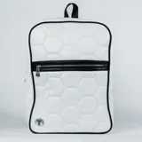 Mochila Tiffosi de diseño acolchado con patrón hexagonal similar a una pelota de fútbol. Presenta un color blanco predominante con detalles en negro en los bordes y el cierre frontal, además de un aplique metálico circular con el logo de la marca en la esquina inferior.
