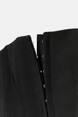 Top tipo corset de escote recto y hombros descubiertos, con cierre frontal mediante ganchos metálicos y costuras verticales estructuradas.