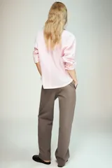 Camisa de popelín color rosa pálido, con cuello solapa, escote pico y manga larga terminada en puño. Cierre frontal con botones.