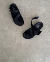 Sandalias negras de cuero vacuno con tiras cruzadas y hebilla lateral.