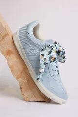 Zapatillas bajas color marrón con cordones y charms dorados.