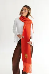 Bufanda de algodón color marrón con flecos en los extremos y logo bordado en amarillo.