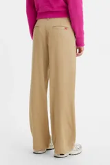 Pantalón de corte baggy en color beige, con diseño de tiro medio y pernera ancha. Presenta cierre frontal con botón y cremallera, y bolsillos laterales.