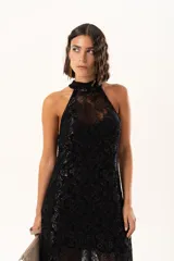 Vestido largo de encaje negro con destellos de lurex, diseño de cuello halter y tajos laterales. Incluye un vestido corto removible como forro interno.
