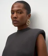 Chaleco de punto negro con cuello redondo, hombreras estructuradas y diseño sin mangas. Confeccionado en tejido de punto con acabado acanalado en el ruedo.