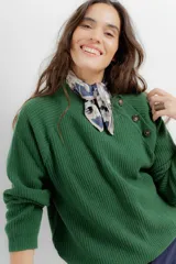 Sweater de punto en color crema con rayas horizontales en tono dorado. Presenta un diseño de cuello redondo con una solapa lateral decorada con botones metálicos dorados y corte holgado.