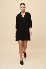 Vestido corto negro de silueta relajada, con escote en V y mangas 3/4 levemente abullonadas.