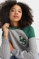 Buzo gris con mangas raglán verde oscuro y logo bordado en el pecho.