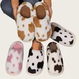 Pantuflas sin talón confeccionadas en algodón afelpado y piel sintética, con divertido estampado de manchas de vaca en tonos blanco y marrón, y suela de PVC.